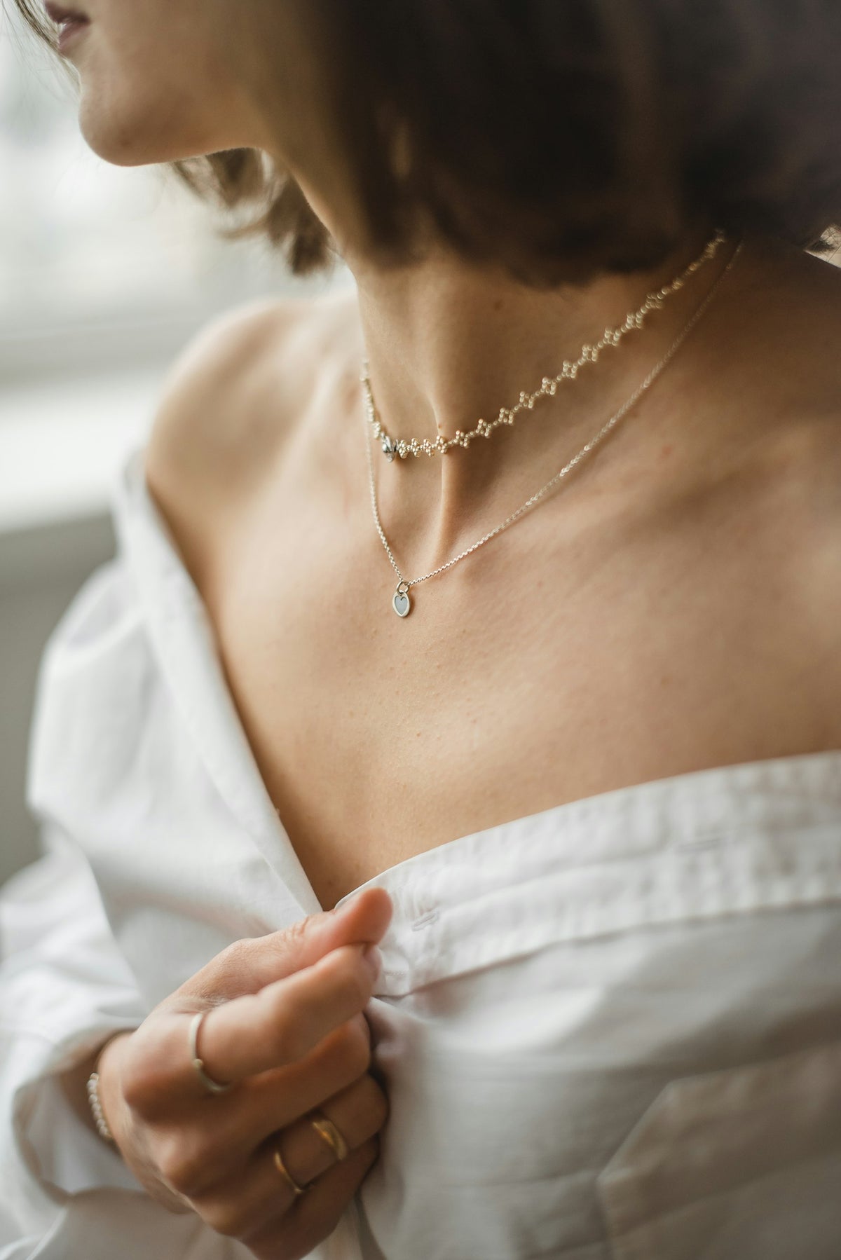 A woman in a white off-shoulder top wearing a silver necklace