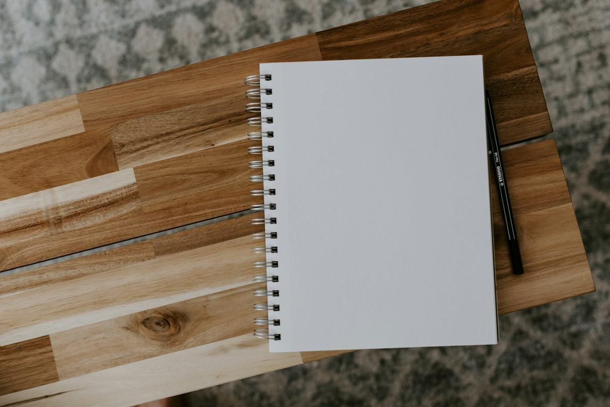 A blank spiral notebook on a wooden desk, waiting to be written in